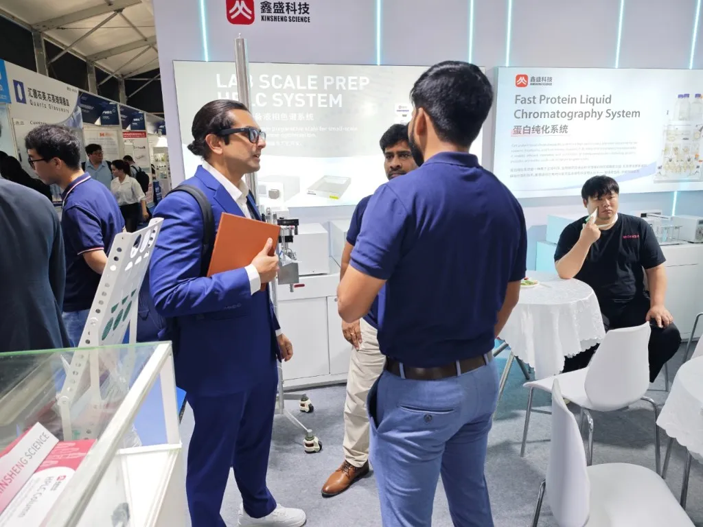 DSP team discussing Lab Scale Prep HPLC system with visitor at exhibition booth